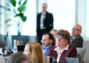 Woman in glasses with event attendees in background